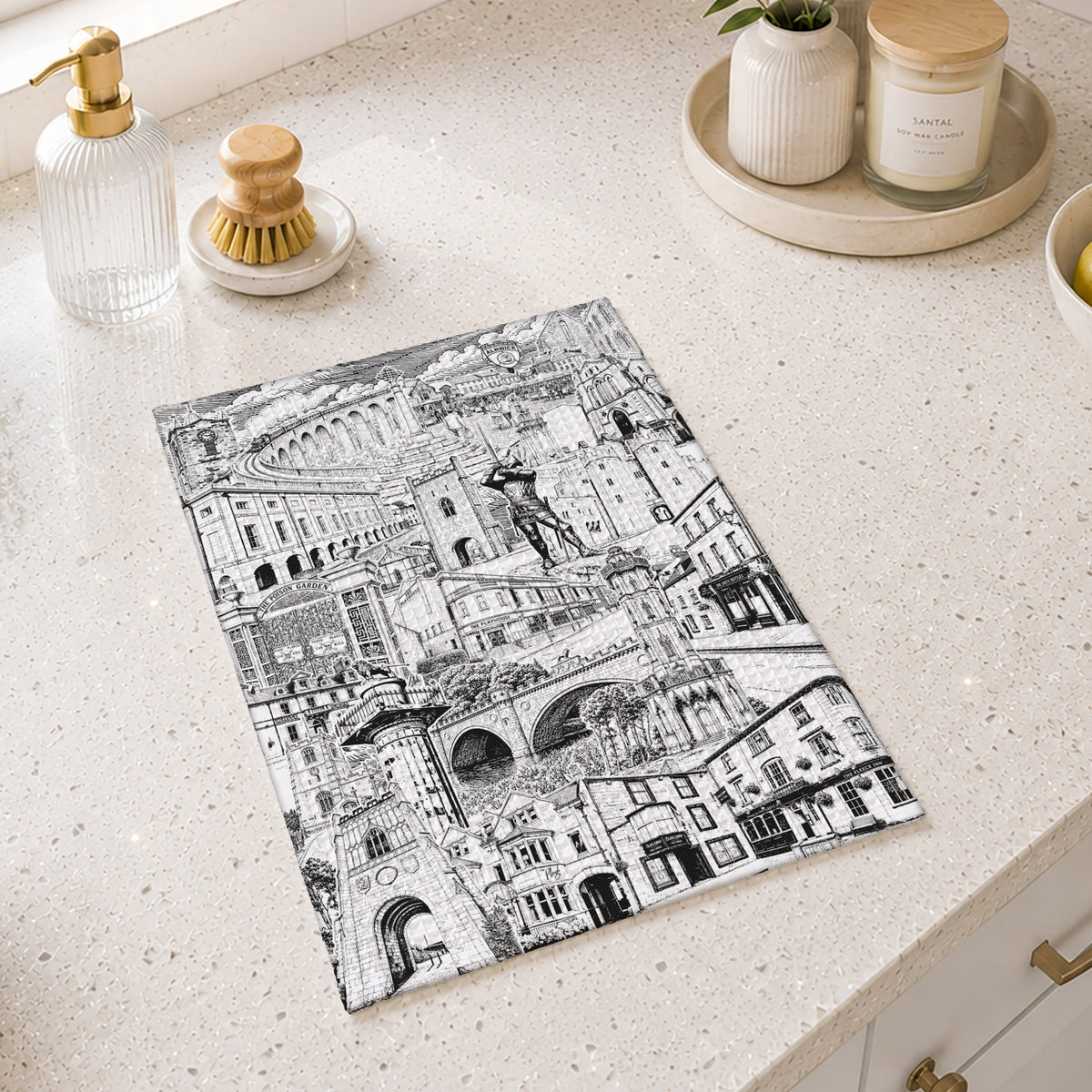 A rectangular kitchen towel with a black and white architectural illustration of Alnwick Northumberland