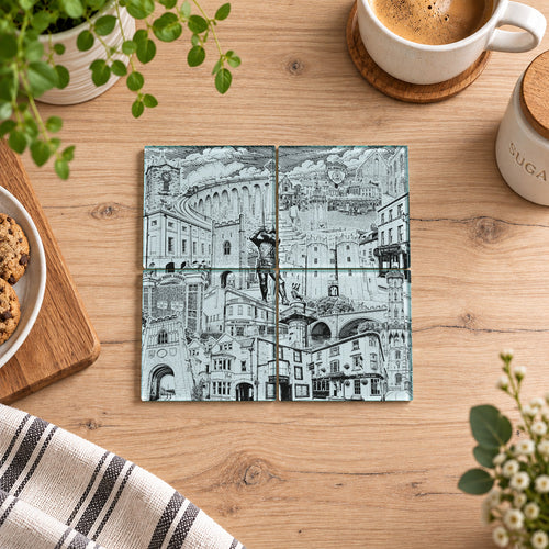 Four square ceramic coasters with a black and white architectural illustration of an Italian city, arranged on a light wood tabletop surrounded by coffee cups, a striped napkin, and green plants.