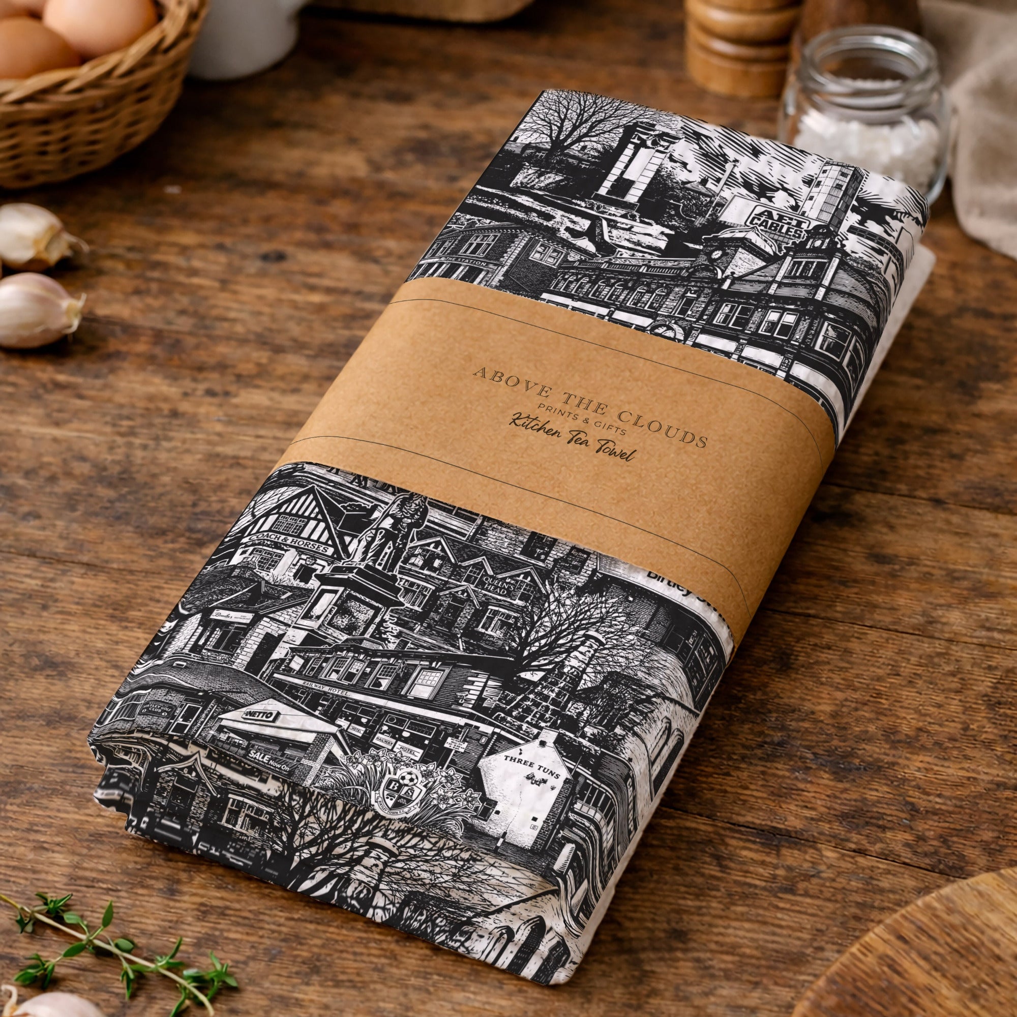 Folded fabric with black and white pattern on a wooden surface with kitchen items.