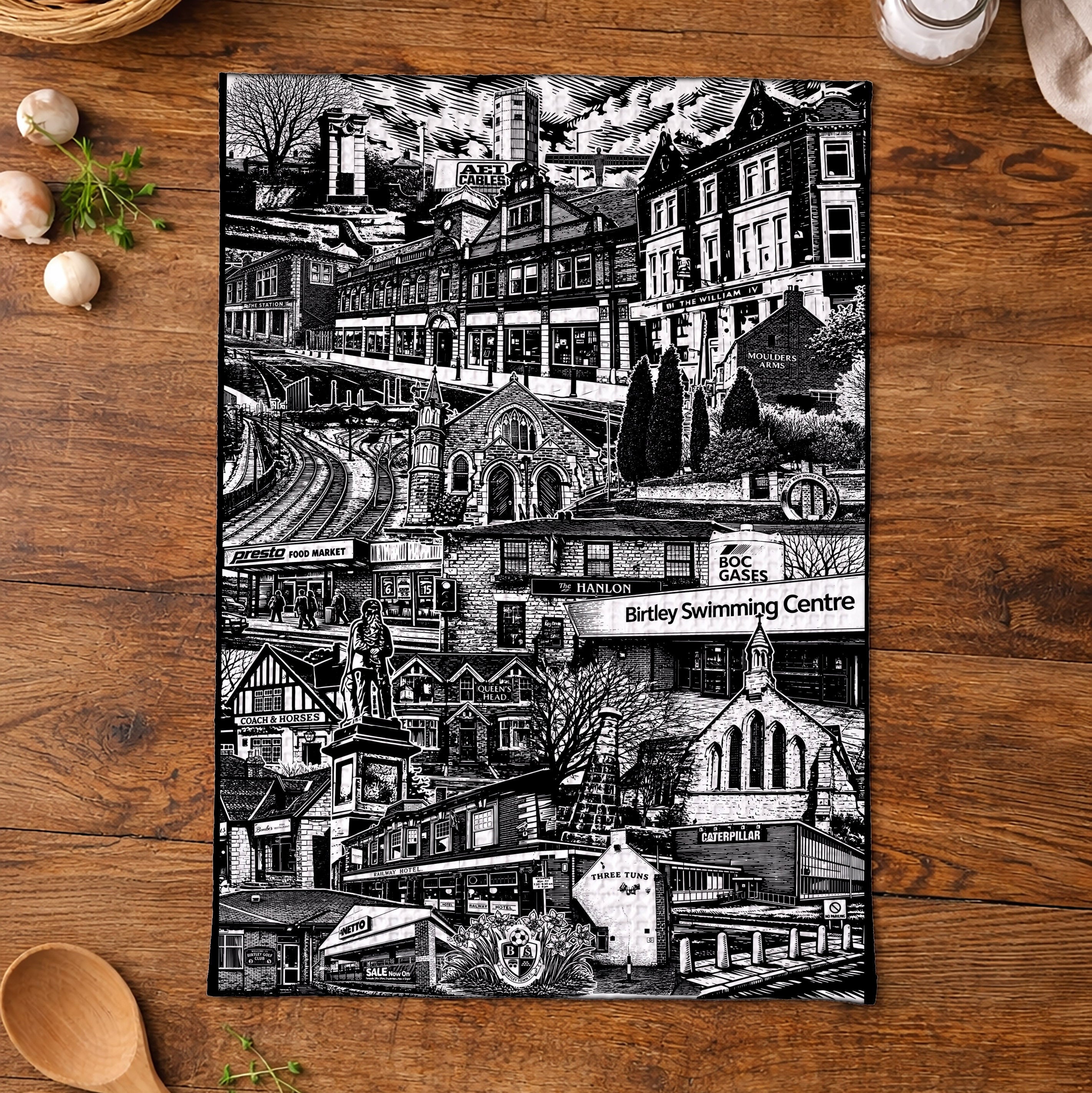 Black and white print of a town scene on a wooden surface with kitchen items.