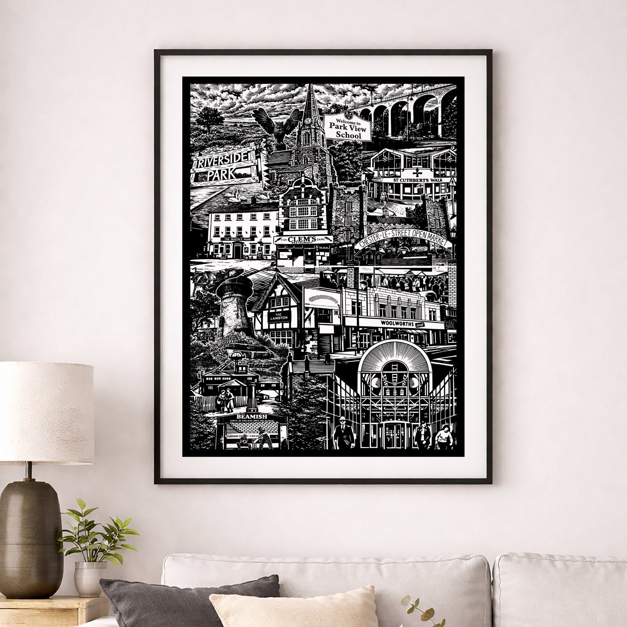 Framed black and white cityscape print on a wall above a sofa in a living room.