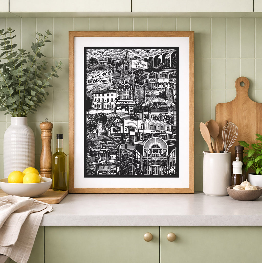 Framed black and white print on a kitchen counter with green cabinets and decor.