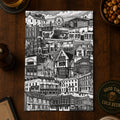 Black and white cityscape print on a wooden table with drinks and a menu.