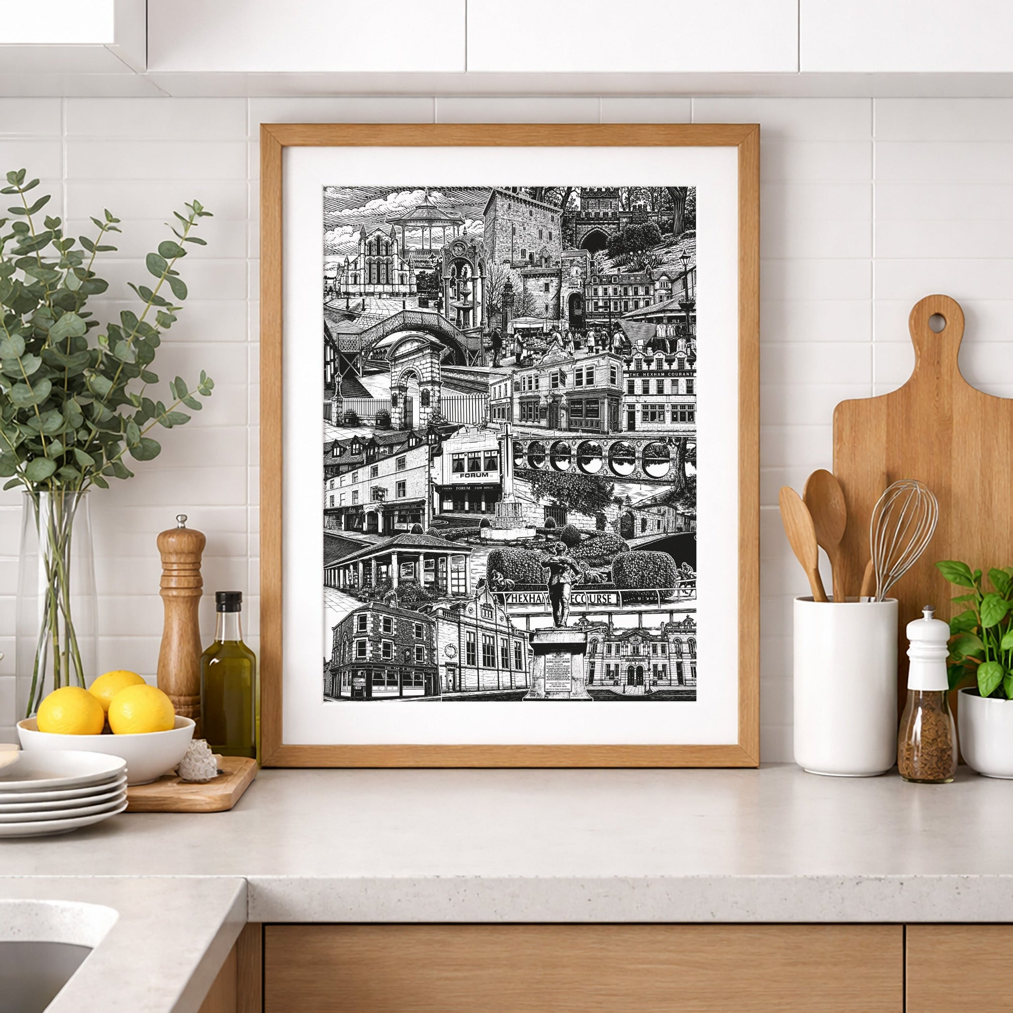 Framed black and white print on a kitchen wall with wooden cabinets and white countertops.