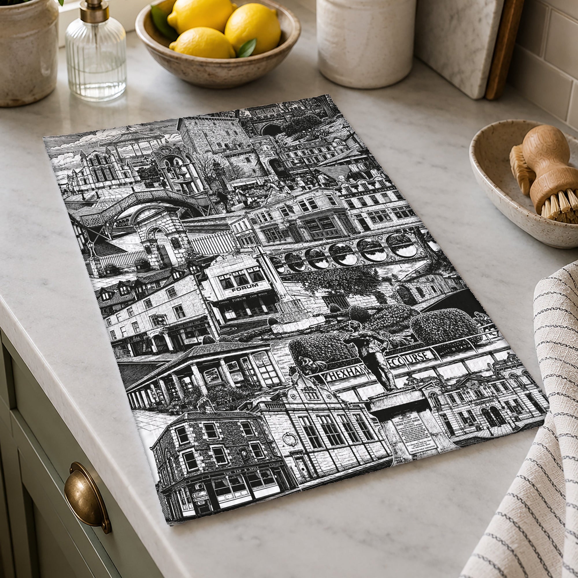 Black and white patterned towel on a kitchen counter with lemons and utensils in the background.