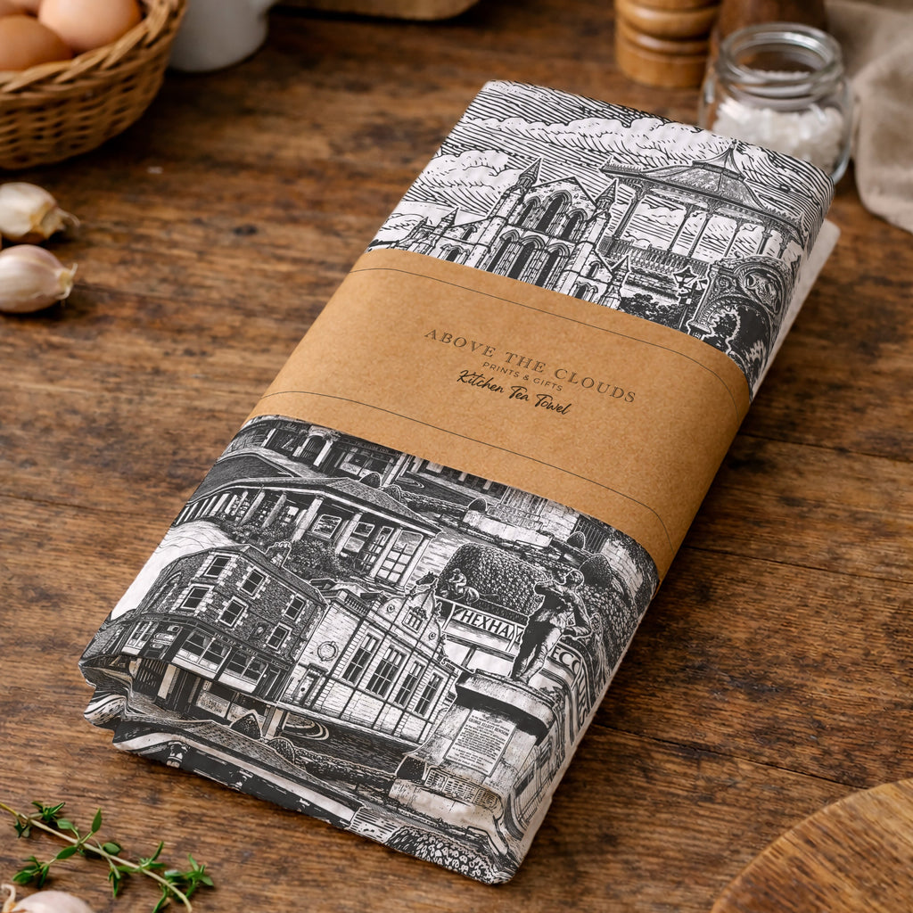 Kitchen towel with black and white design and brown label on a wooden table