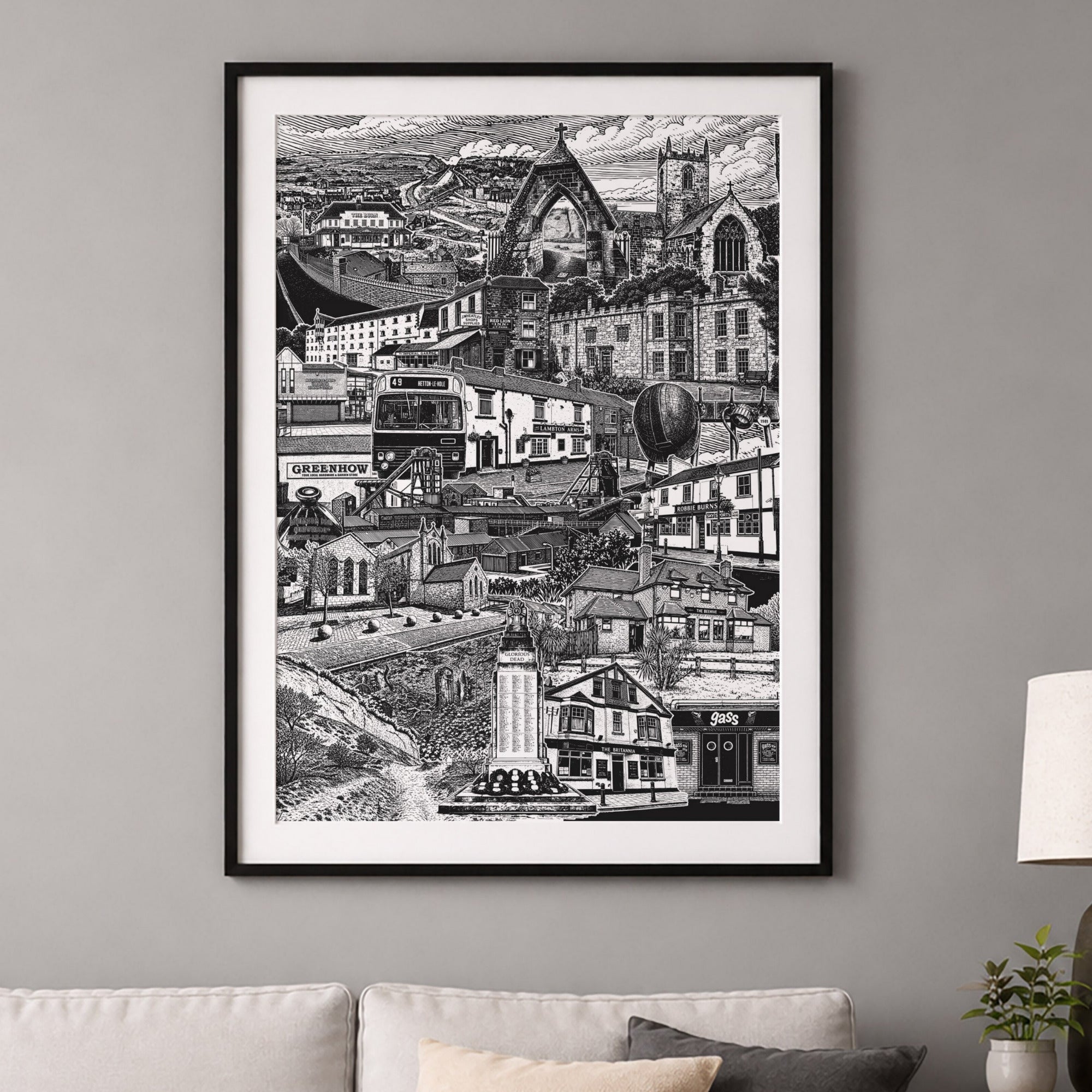 Framed black and white cityscape print on a gray wall above a sofa.