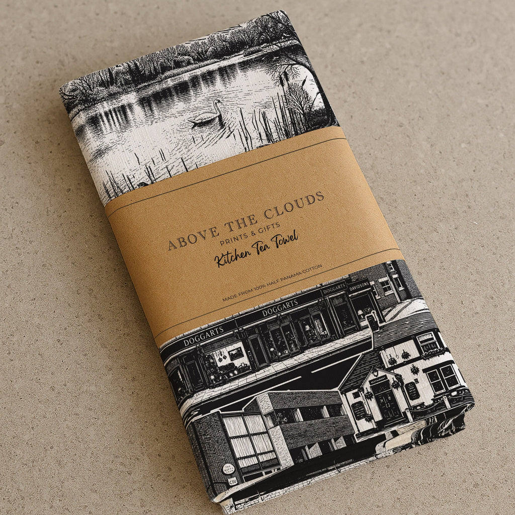 Folded tea towel with black and white pattern and brown label on a beige background