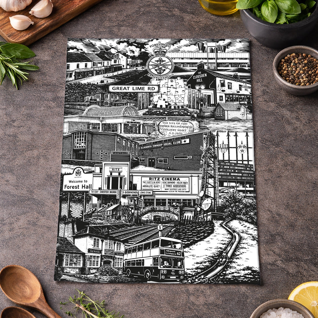 Tea towel with black and white cityscape design on a kitchen counter with ingredients.