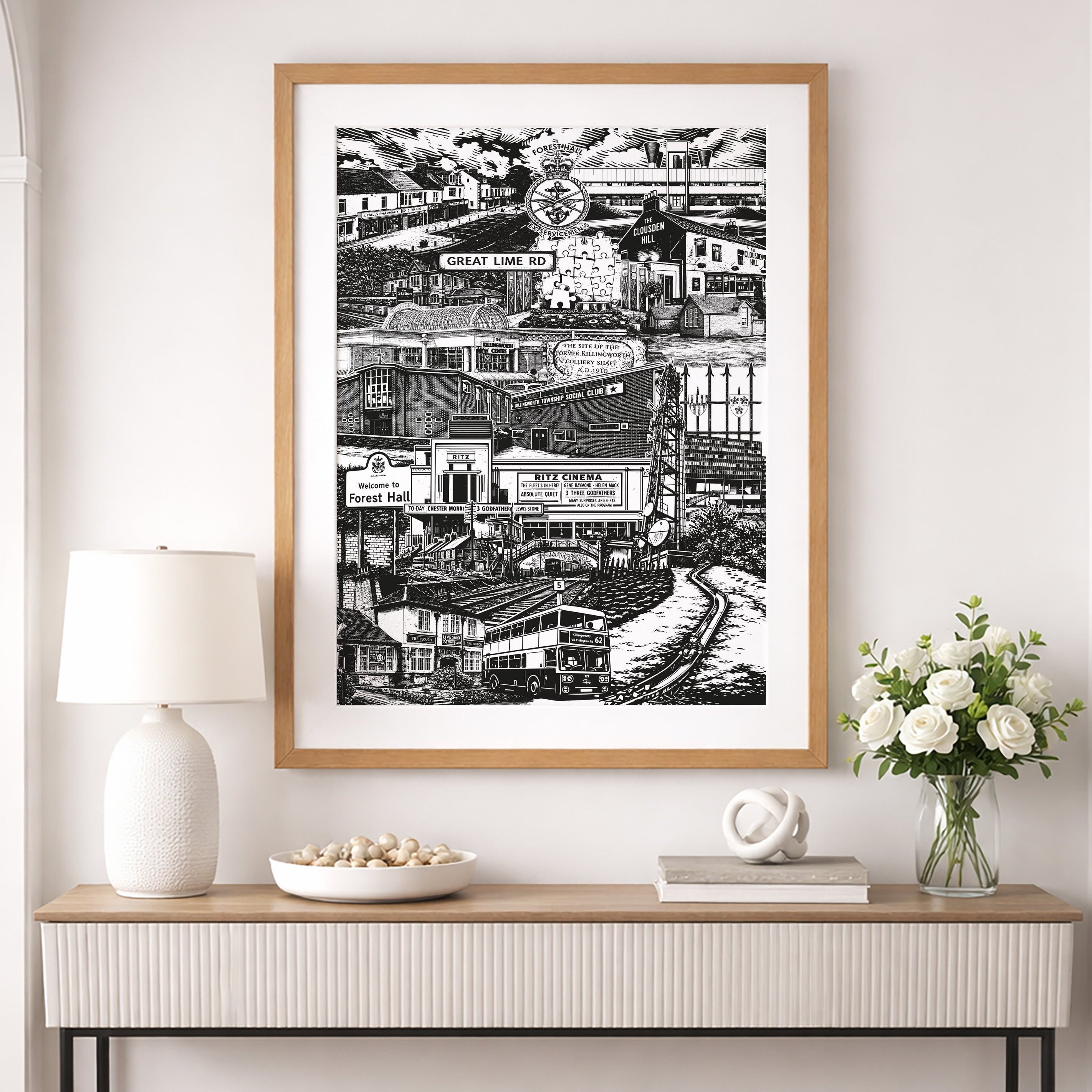 Framed black and white artwork on a wall above a console table with decorative items.
