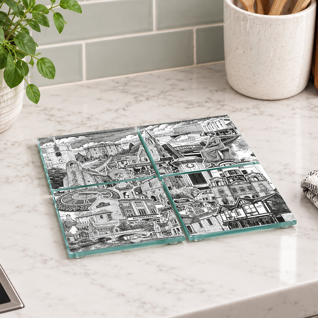 Four square glass coasters with a black and white architectural collage print, arranged in a 2x2 grid on a white marble kitchen countertop.