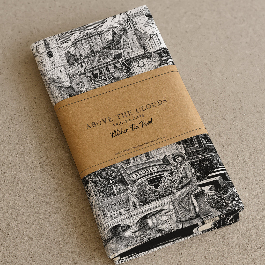 A folded morpeth themed kitchen towel with a black and white vintage architectural illustration, wrapped in a tan paper band that reads 'ABOVE THE CLOUDS'