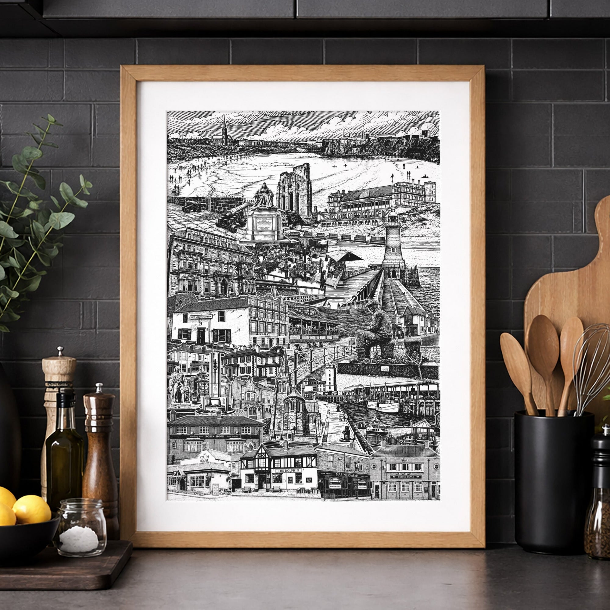 Framed black and white cityscape print on a kitchen wall with dark cabinets and countertop.