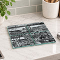 Four square glass coasters with a black and white architectural cityscape print, arranged on a white marble kitchen countertop.