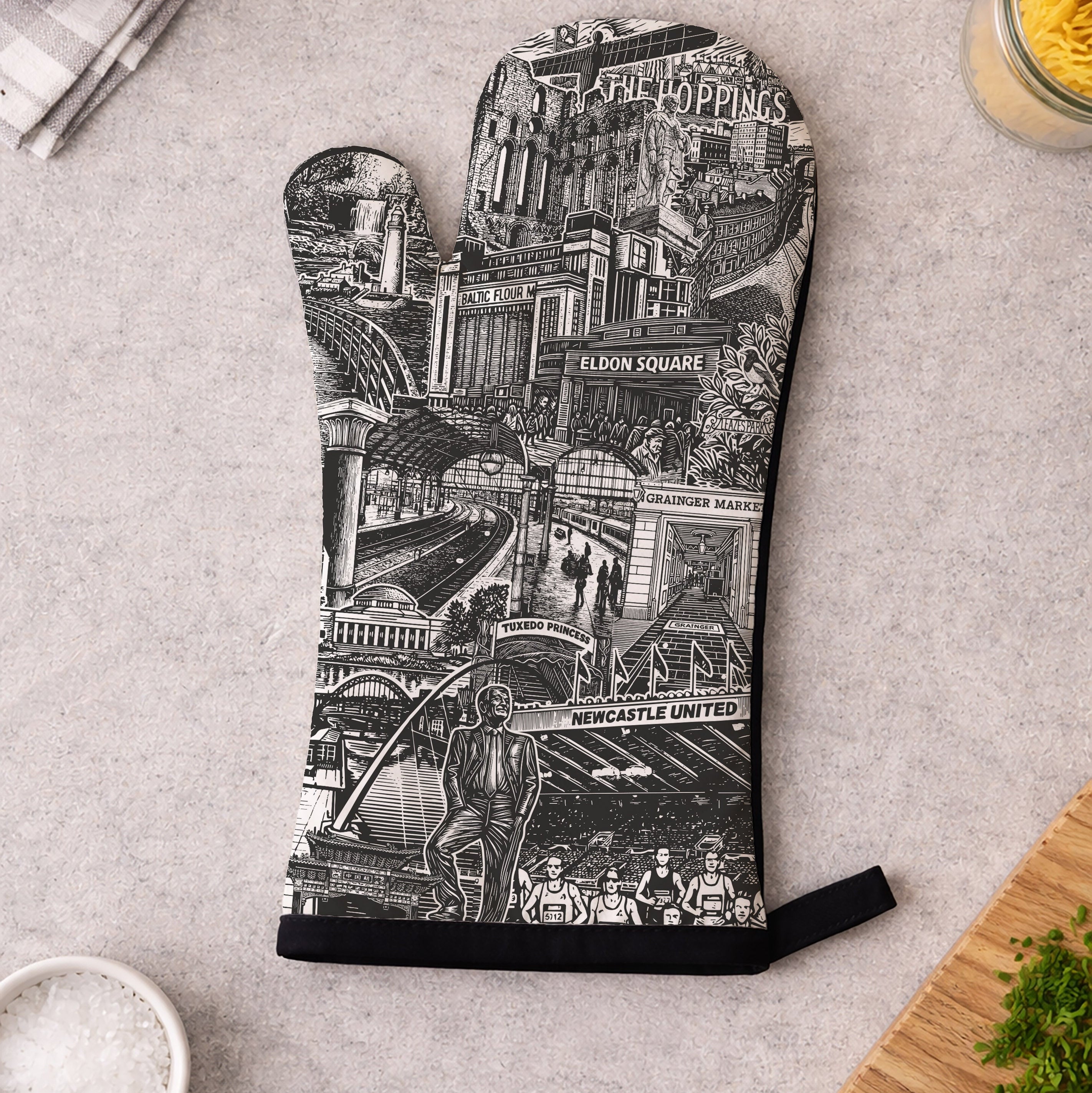 Oven mitt with a black and white design of a stadium on a gray surface.