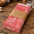 Folded red and white patterned fabric with brown paper wrap on a wooden surface