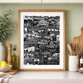 Framed black and white print on a kitchen counter with green cabinets and decor.
