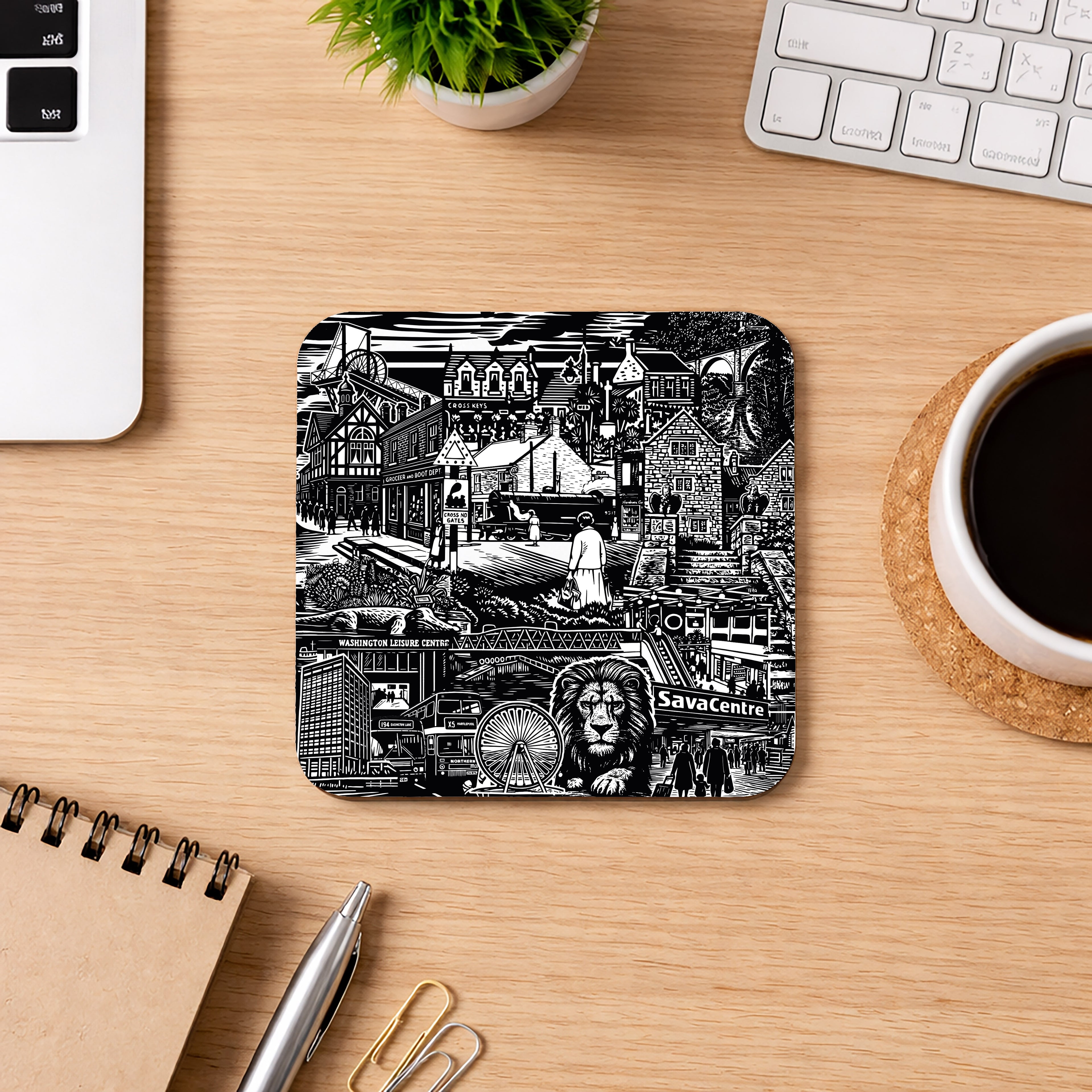 Coaster with black and white cityscape design on a wooden desk with a cup of coffee, laptop, and notebook.
