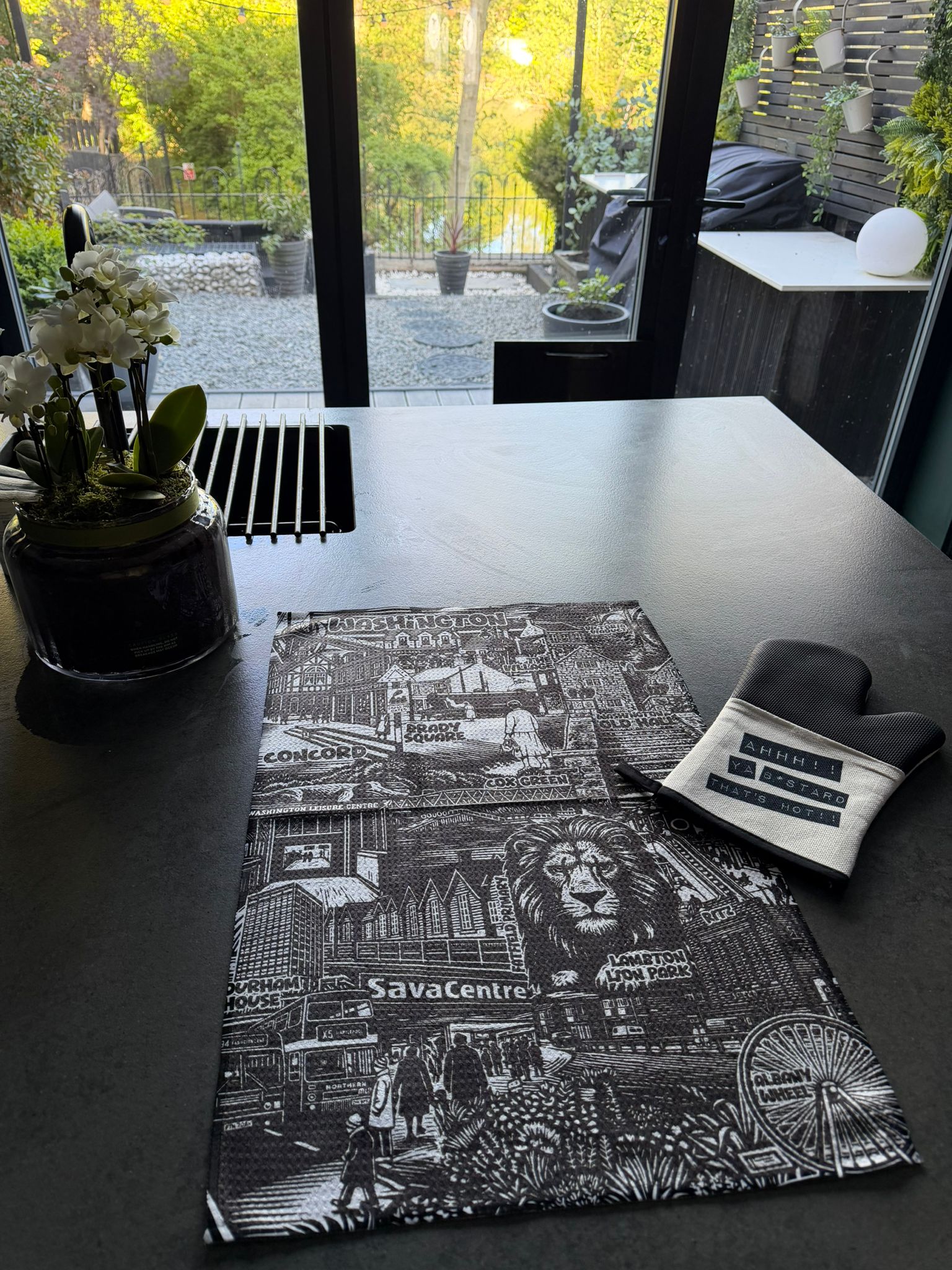 Table with a decorative placemat featuring cityscape design and a small pillow.