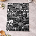 Black and white patterned towel on a kitchen counter with wooden spoons and eggs.