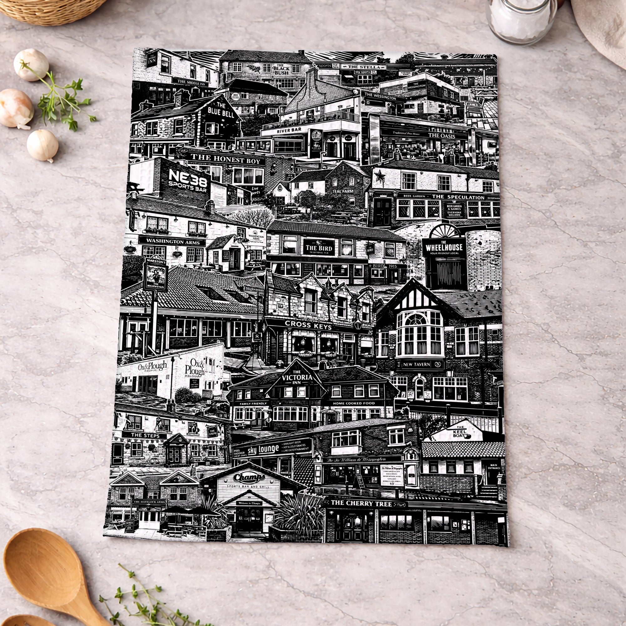 Black and white patterned towel on a kitchen counter with wooden spoons and eggs.