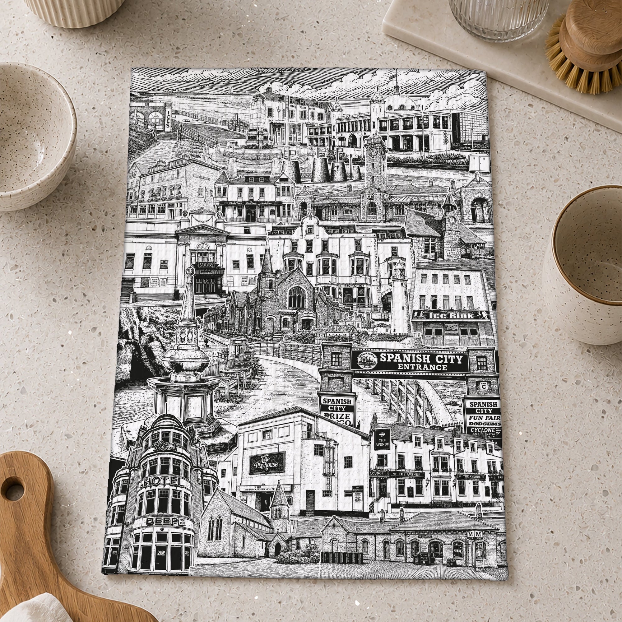 Black and white cityscape tea towel on a kitchen counter with utensils.