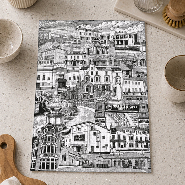 Black and white cityscape tea towel on a kitchen counter with utensils.