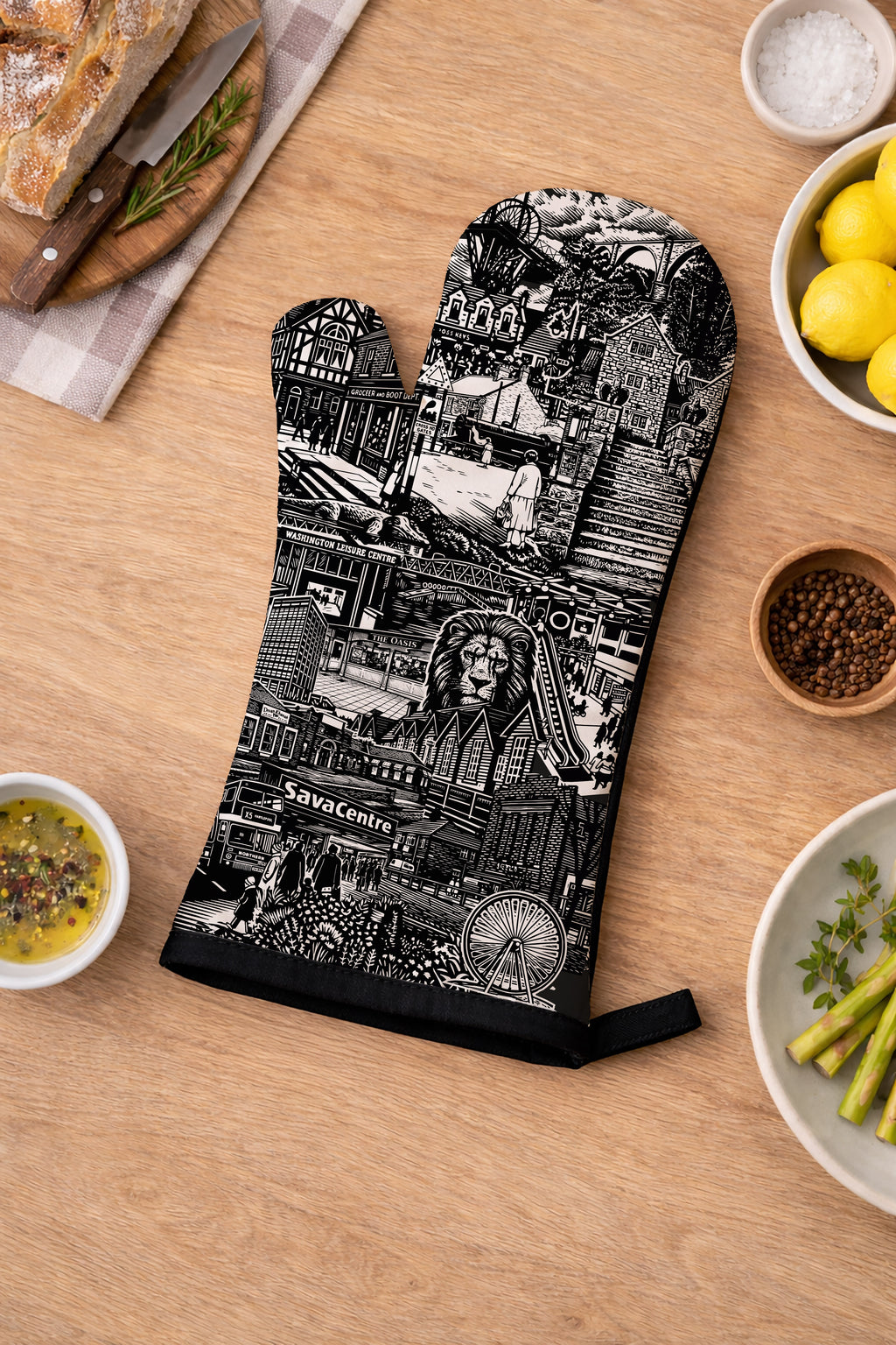 Oven mitt with black and white design on a wooden table with food items.
